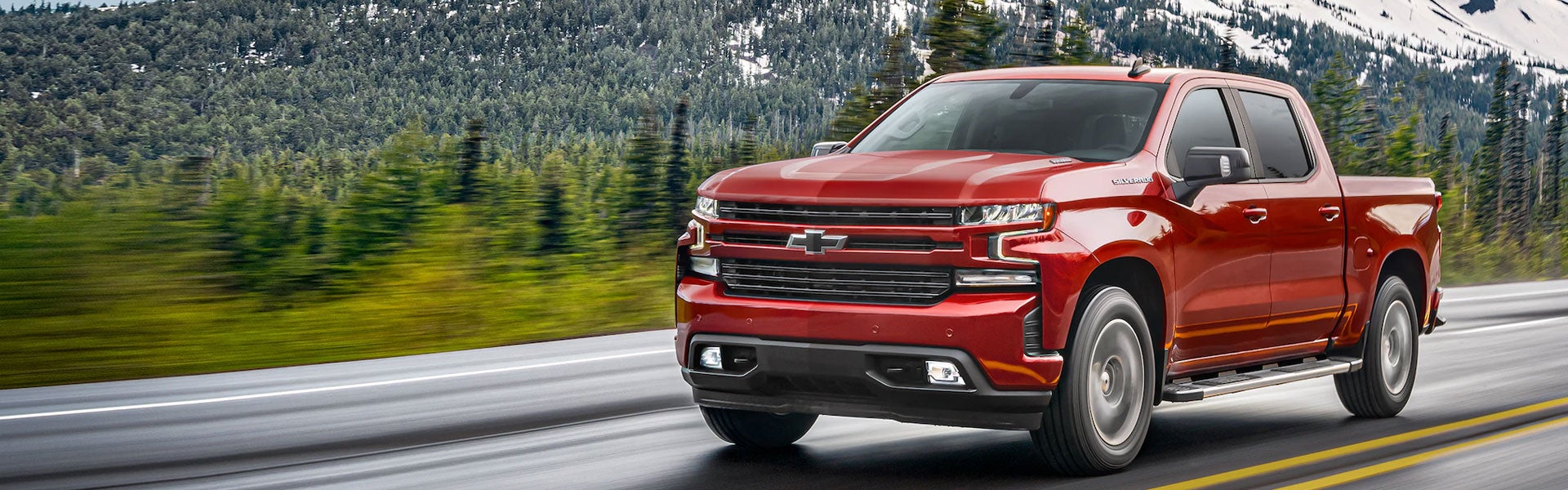 Red Chevrolet Silverado 1500 driving on a scenic mountain road