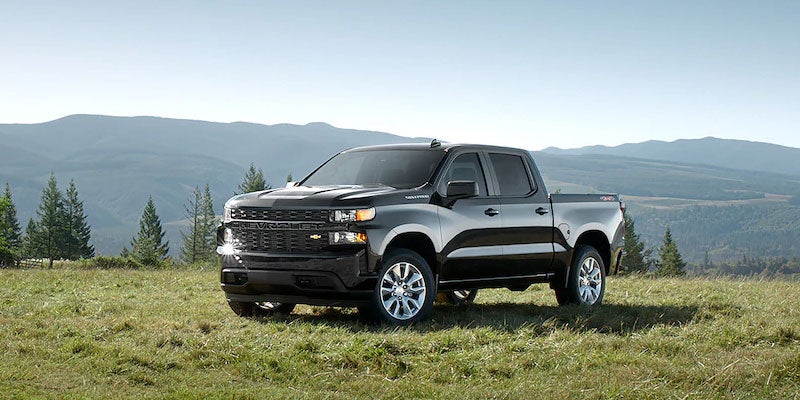 Black Silverado standing on grass near hills