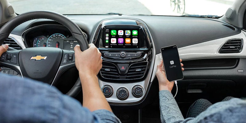 A men is Driving a Chevrolet Spark and a women is holding a mobile in hand