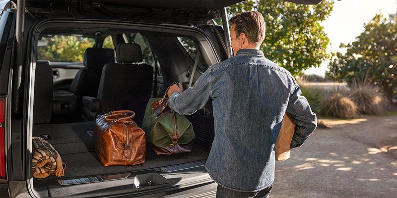 A men is unloading luggage from Chevrolet Tahoe