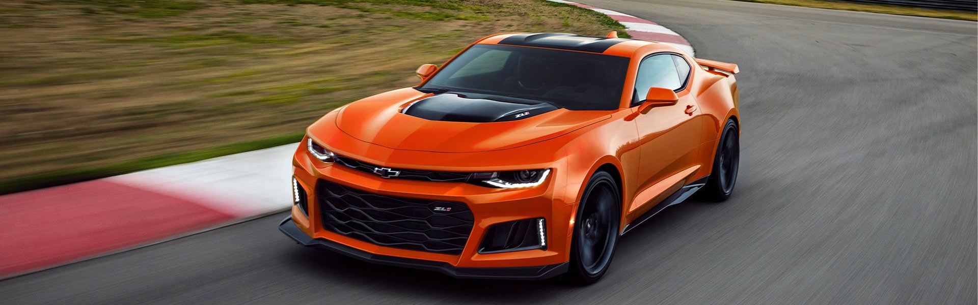 Orange Chevrolet Camaro running on race track road