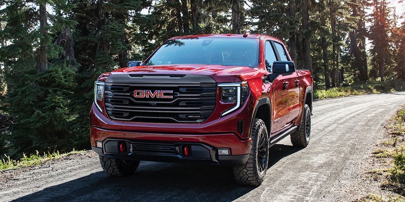 Red GMC Sierra driving on a tree-lined road