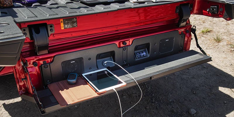 Red GMC Sierra tailgate open with power outlets and tablet
